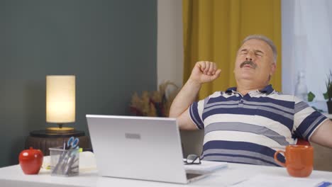 Home-office-worker-old-man-yawns-and-relaxes-at-the-camera.